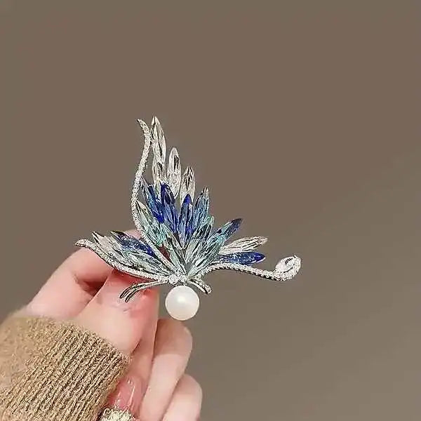 silver butterfly brooch with folded wings set in blue zircon and crystal plus a pearl held like a treasure by Butterfly Aura