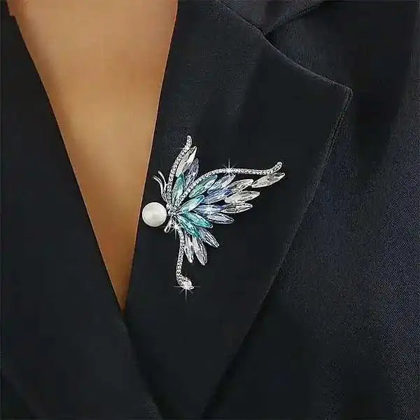 silver butterfly brooch with folded wings set in blue zircon and crystal plus a pearl held like a treasure by Butterfly Aura